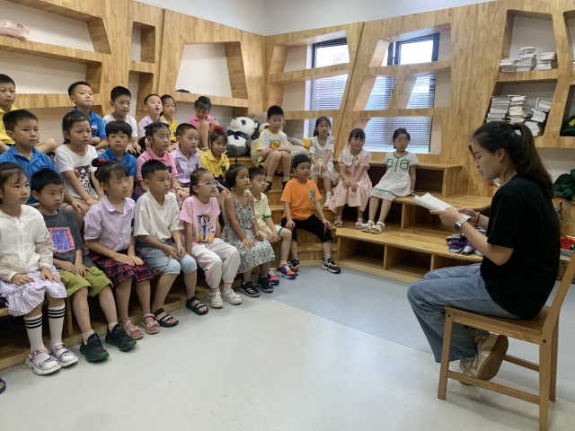 图为暑托班的孩子在听老师讲故事 北仑区教育局供图.jpg