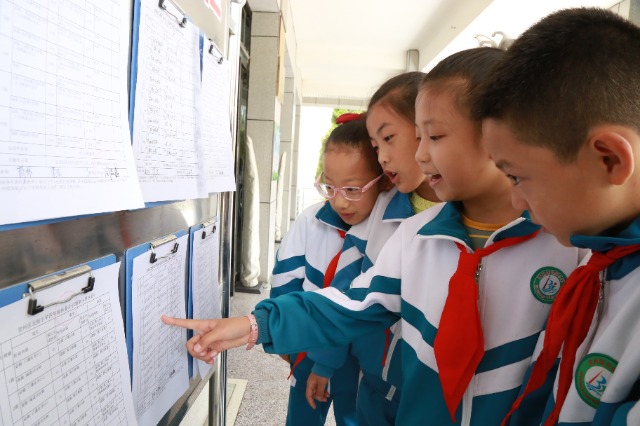 甘州区北街小学孩子在围观公示出的作业清单（张儒泰摄）.JPG