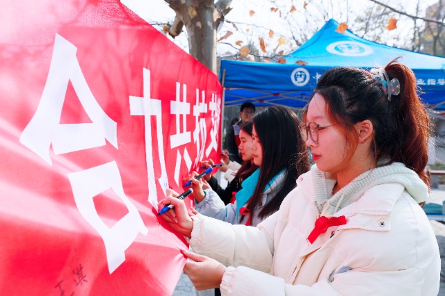 20231127中国石油大学（华东）青年学子在合力共抗艾滋的条幅上签字，表达抗击艾滋病的决心和信心  .jpg