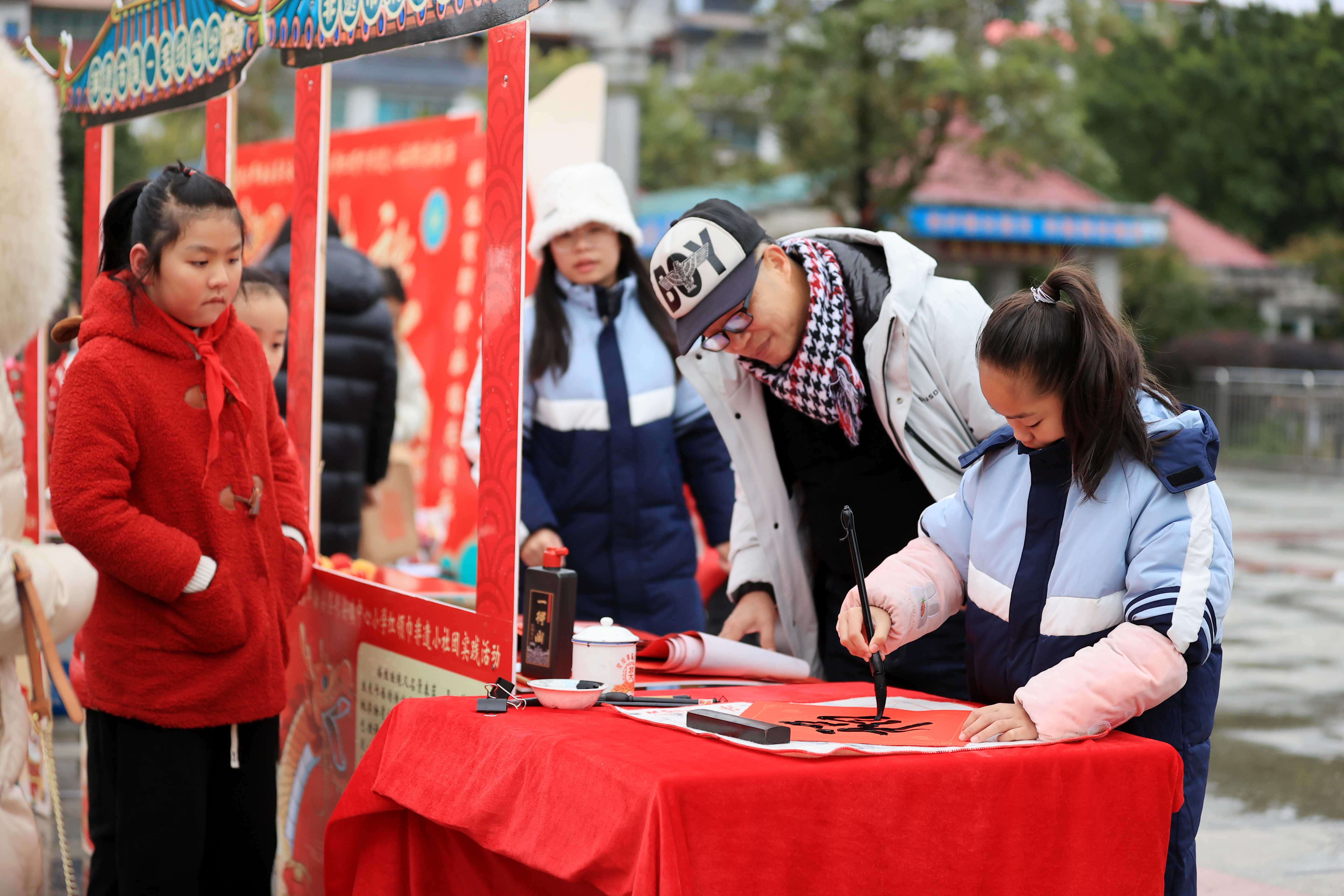 图10：1月20日，在广西柳州市融安县长安广场，一名小学生在书写福字，准备赠送市民。（谭凯兴 摄）.JPG
